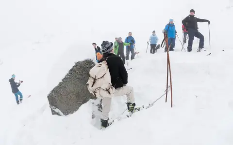 Grupa turystów w śnieżnej scenerii, jeden z nich z plecakiem, jakby szukał krzyża niespodzianego.