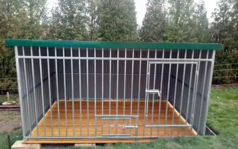 Solidny kojec dla psa z paneli ogrodzeniowych, z drewnianą podłogą i zielonym dachem. Idealne miejsce dla czworonoga.
