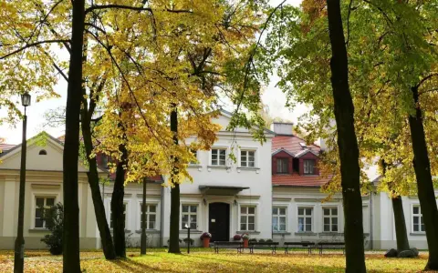 Jesienny spacer wokół dworu Zbożenna. Złote liście drzew otulają zabytkowy budynek.