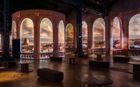 Une projection immersive d'une ville italienne, évoquant la splendeur de la renaissance italienne, avec des arches et un ciel dramatique.