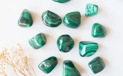 Tumbled malachite stones with their characteristic green bands, showcasing the beauty and potential malachite proprietà.