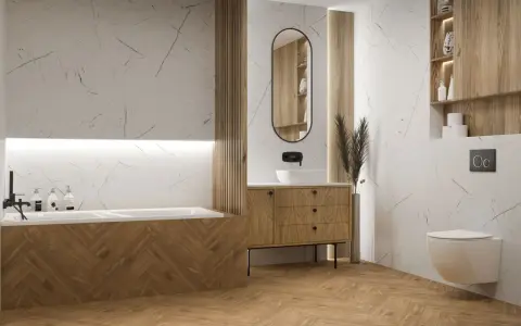 Nowoczesna łazienka z wanną i umywalką. Wzrok przyciągają płytki w jodełkę na ścianie przy wannie i na podłodze, tworząc ciepły, drewniany klimat.
