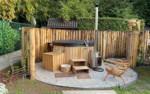 Entspannende gartendusche ideen: Ein Whirlpool mit Holzverkleidung, daneben ein Holzofen und Sitzgelegenheiten aus Holz.