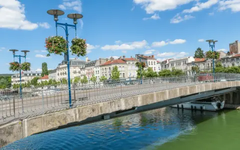 Pont fleuri sur la Meuse, une belle journée pour visiter Verdun en 1 jour. Ville historique avec des bâtiments anciens et un ciel bleu.
