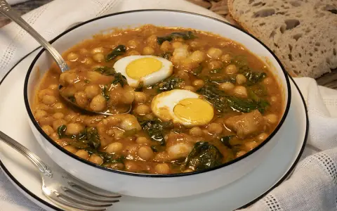 Potaje de garbanzos con bacalao y huevo duro en un cuenco blanco.