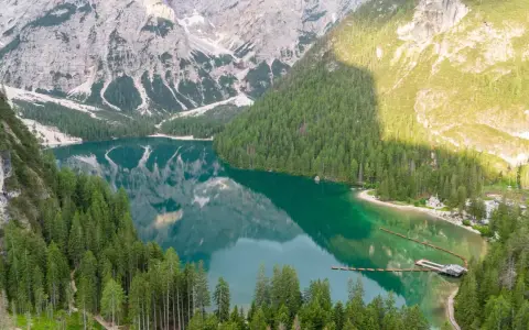 Un lago alpino dai riflessi smeraldo, incorniciato da boschi di conifere e montagne imponenti. Un gioiello tra i quattro laghi del nord Italia.