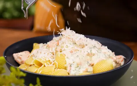 En krämig lax pasta med crème fraîche toppas med riven ost.