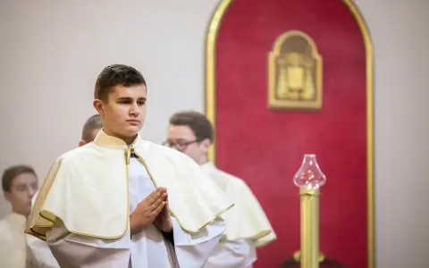 Junge Männer in festlicher Kleidung, die auf ihre Diakon Ausbildung vorbereitet werden. Sie stehen betend in einer Kirche.