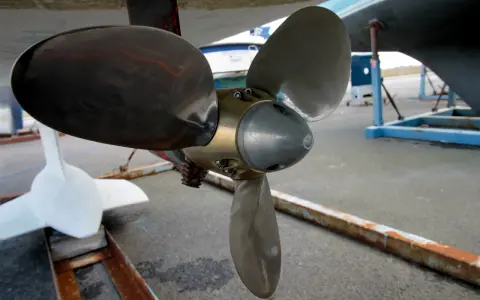 Gros plan sur l'hélice d'un bateau, prête pour son nettoyage. Une autre hélice blanche est visible à gauche.