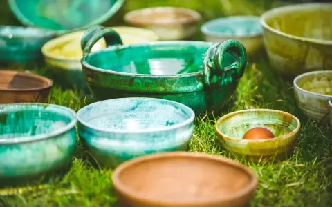 Varietà di ciotole in ceramica smaltata, che ricordano diversi tipi di argilla per modellare, disposte sull'erba.
