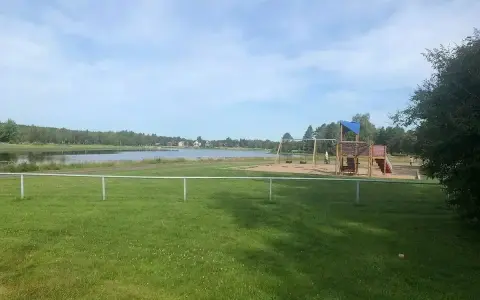 Lekplats med gungor och klätterställning vid en sjö, perfekt för familjer på Malung camping.