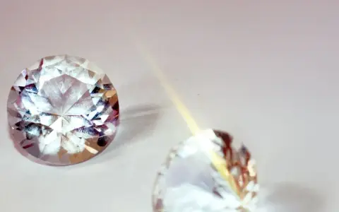 Due pietre preziose scintillanti, una sfaccettata e luminosa, l'altra più sfocata, illustrano la differenza tra brillanti e diamanti.