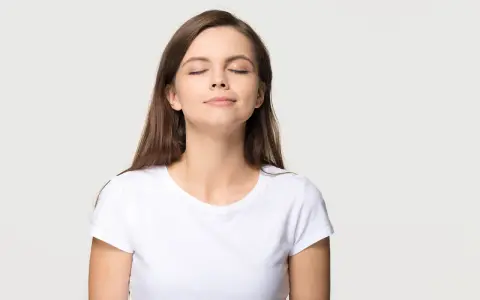 Frau mit geschlossenen Augen, die tief durchatmet. Eine Übung zur Lippenbremse kann bei Asthma helfen, die Atmung zu kontrollieren.