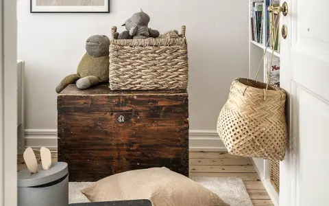 Cesti di vimini per idee arredare con stile: un cesto intrecciato sopra un baule antico, un altro appeso alla porta.