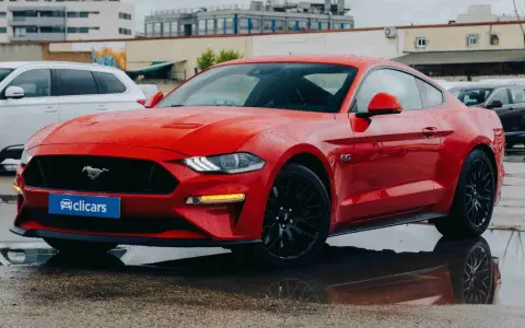 Un deportivo rojo, que es un coche coupe, brilla bajo la lluvia.