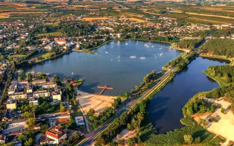 Widok z lotu ptaka na zalew Mrożyczka, z wakeboardzistami, plażą i otaczającą zielenią.