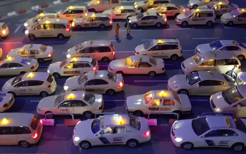 Modellautos von Taxis stehen im Stau. Die Lichter leuchten, als ob sie Nachtzuschlag berechnen würden.