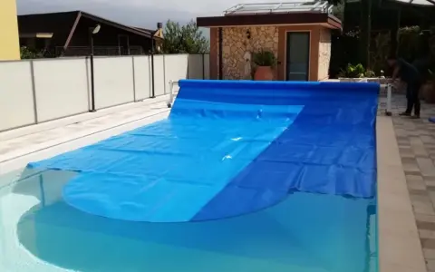 Cubierta azul para piscina, ideal para saber como calentar el agua de la piscina y mantenerla limpia.