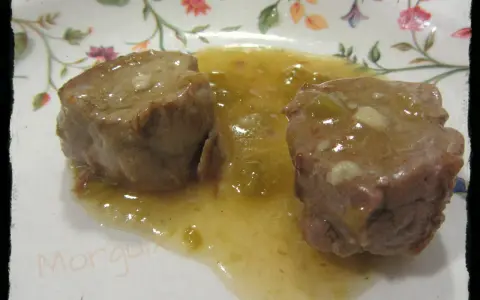 Dos trozos de solomillo al whisky en una salsa dorada, servidos en un plato con flores.