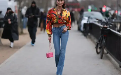 Stylische Frau in bunten Jackett und bootcut jeans kombinieren mit pinker Tasche und auffälligen Schuhen.