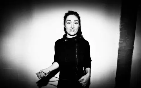 Paula Temple, DJ, con auriculares alrededor del cuello, sostiene cables de audio.