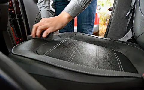 Hand reinigt Autositz aus Leder mit einem Tuch. Hausmittel für Leder reinigen sind eine gute Wahl.