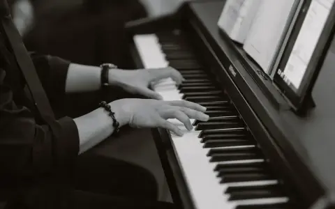 Dłonie grające na pianinie, tworząc improwizowany kierunek w muzyce jazzowej.