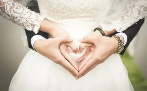 Manos formando un corazón sobre el vestido de novia, símbolo de una boda de platino.
