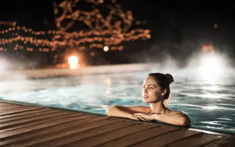 Entspannter Abend in den Thermen NRW. Eine Frau genießt das warme Wasser, umgeben von stimmungsvoller Beleuchtung und Dampf.