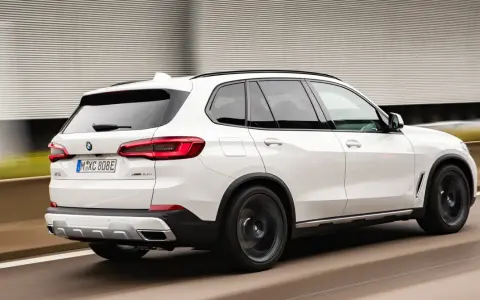 Białe BMW X5 M50d pędzi po autostradzie, zostawiając za sobą rozmyte tło.