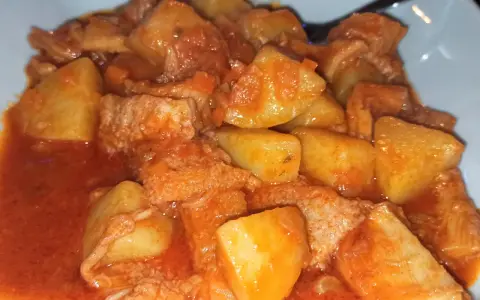 Un piatto fumante di trippa con patate, un classico della cucina italiana, condito con un sugo rosso saporito.