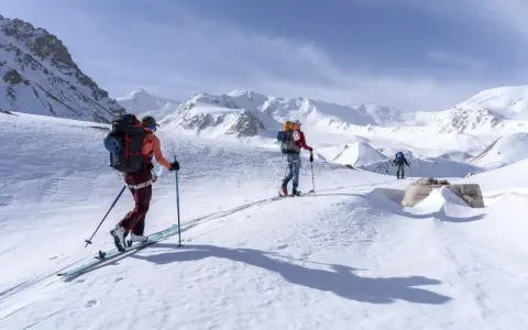 Trois skieurs s'aventurent dans un paysage montagneux enneigé. Une photo ski montagne qui capture l'immensité et la beauté de la nature.