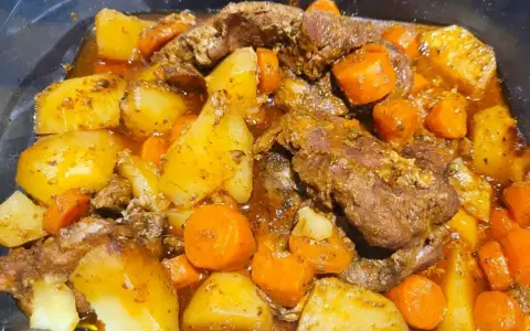 Pyszna karkówka po cygańsku z ziemniakami i marchewką w aromatycznym sosie. Danie wygląda na bardzo sycące i domowe.