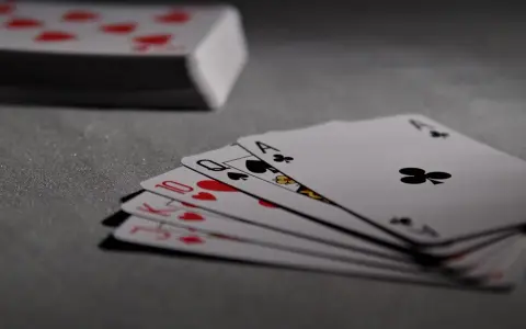 Karty do gry: walet, dama, król i as kier, obok stos kart.