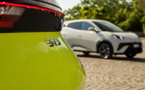 Jasnozielony samochód elektryczny BYD z napisem "310" na klapie bagażnika, w tle biały samochód.