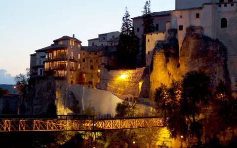 El puente de San Pablo en Cuenca, iluminado de noche, conecta las casas colgantes con la ciudad.