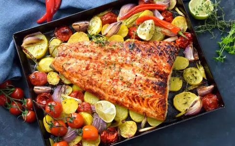 Pescado al horno con patatas, cebolla y tomate, asado a la perfección con hierbas frescas y un toque de limón.