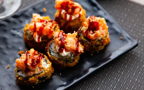 Pięć kawałków sushi w tempurze z łososiem i sosem, idealne na przekąskę.