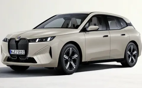 Elegancki, beżowy BMW iX z nowoczesnym grillem i smukłymi światłami.