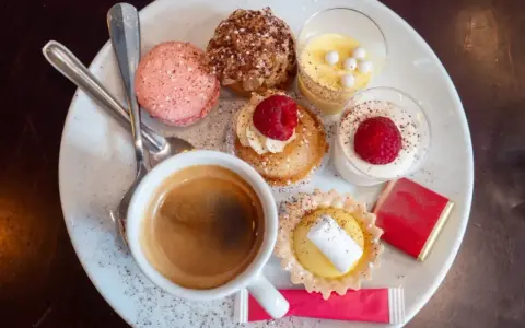 Assortiment de spécialités culinaires parisiennes : macarons, éclairs, tartellettes, verrines et café. Un délice pour les yeux et les papilles.