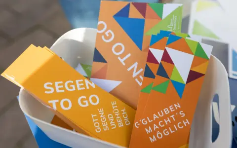 Bunte Karten mit der Aufschrift "Segen to go" und inspirierenden Botschaften wie "Gott segne und behüte dich" liegen in einem Korb.
