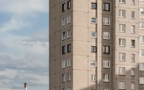 Szare bloki mieszkalne, każde mieszkanie od miasta z oknami wychodzącymi na niebo. W oddali widać komin.