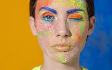 Rostro con maquillaje vibrante y purpurina. ¿Cómo quitar la purpurina de la cara? Este look es un desafío.