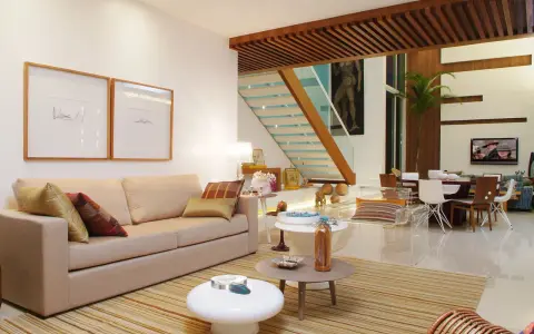 Elegantes salones marrones y beige con sofá, mesas auxiliares, alfombra a rayas y una escalera moderna.