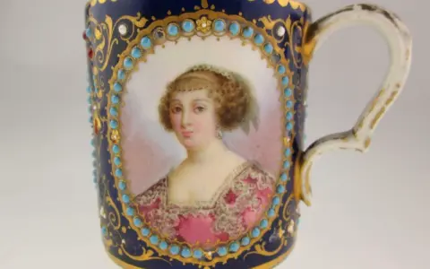 Tasse en porcelaine de Sèvres, ornée d'un portrait féminin, de turquoises et de dorures. La signature de la manufacture est discrètement intégrée.
