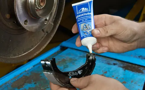 Mechanik nakłada smar ATE Plastilube na szczęki hamulcowe. To właściwy smar do tłoczków hamulcowych, zapewniający płynne działanie układu.