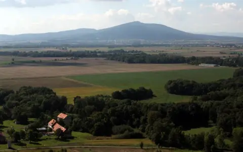 Widok na górzystą okolicę obok Wrocławia z polami, lasami i kilkoma domami.