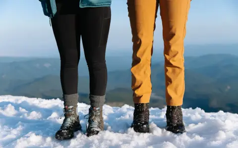 Dwie pary solidnych butów trekkingowych, niczym nowoczesne walonki, stoją na śniegu.