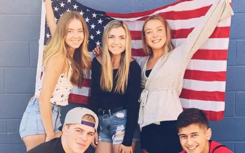 Freunde feiern ihr High School Jahr in den USA vor einer amerikanischen Flagge.