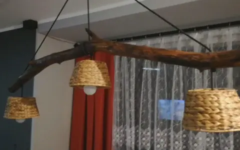 Jak odnowić stary drewniany żyrandol? Ta rustykalna lampa z gałęzi i plecionych kloszy z pewnością doda uroku wnętrzu.